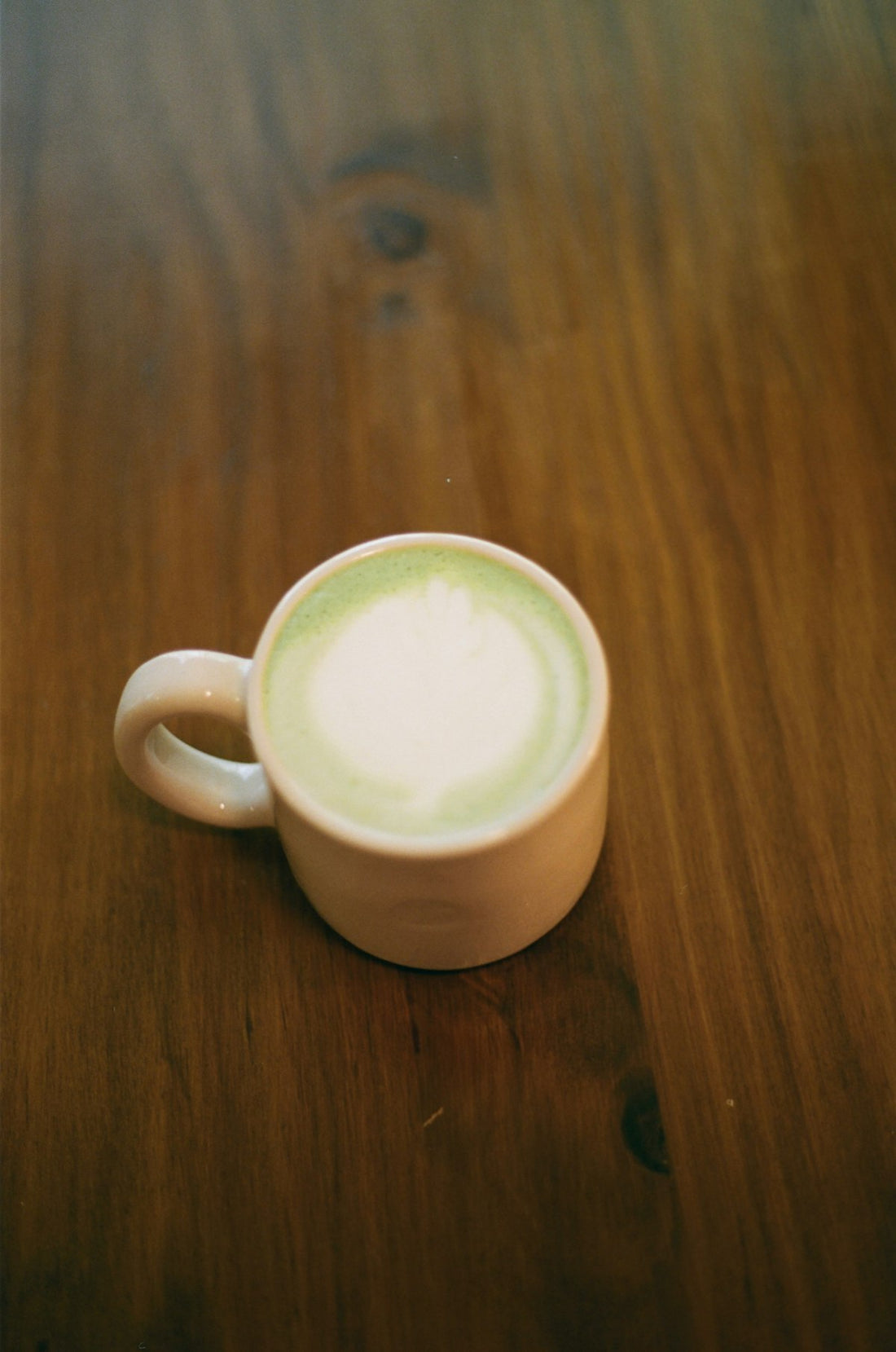 Matcha Latte in einer Keramiktasse mit cremigem Milchschaum, auf Holz serviert