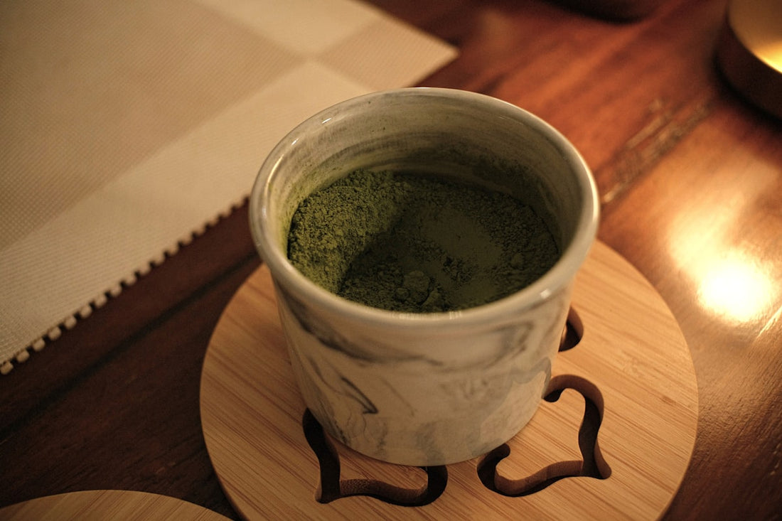 Tasse Matcha-Tee auf einem Untersetzer im warmen Abendlicht auf einem Holztisch